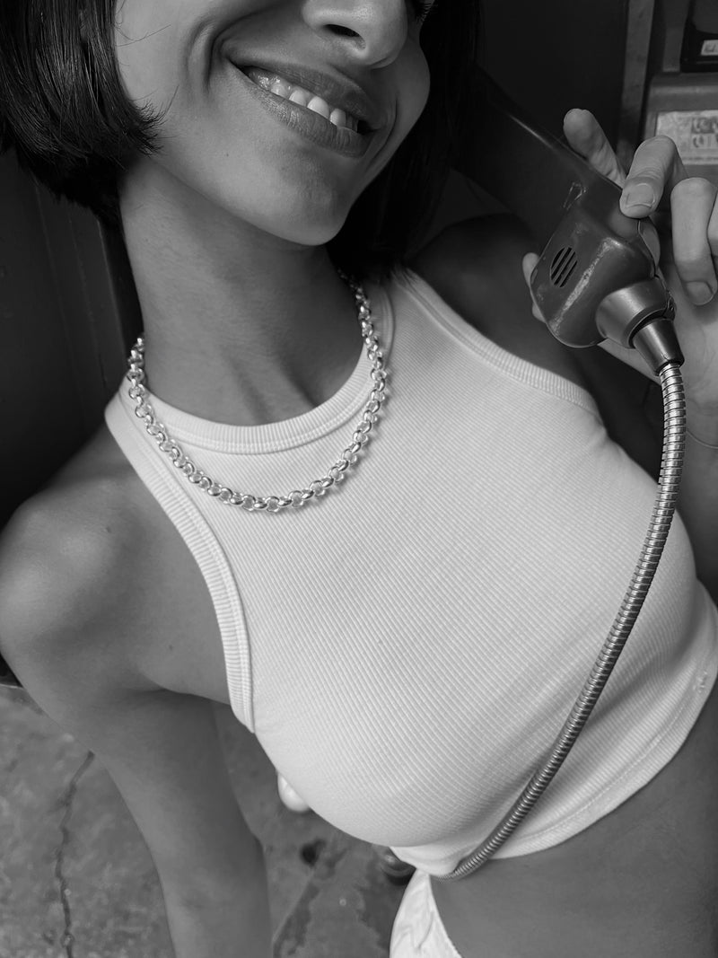 Chunky silver chain necklace on a model holding a telephone